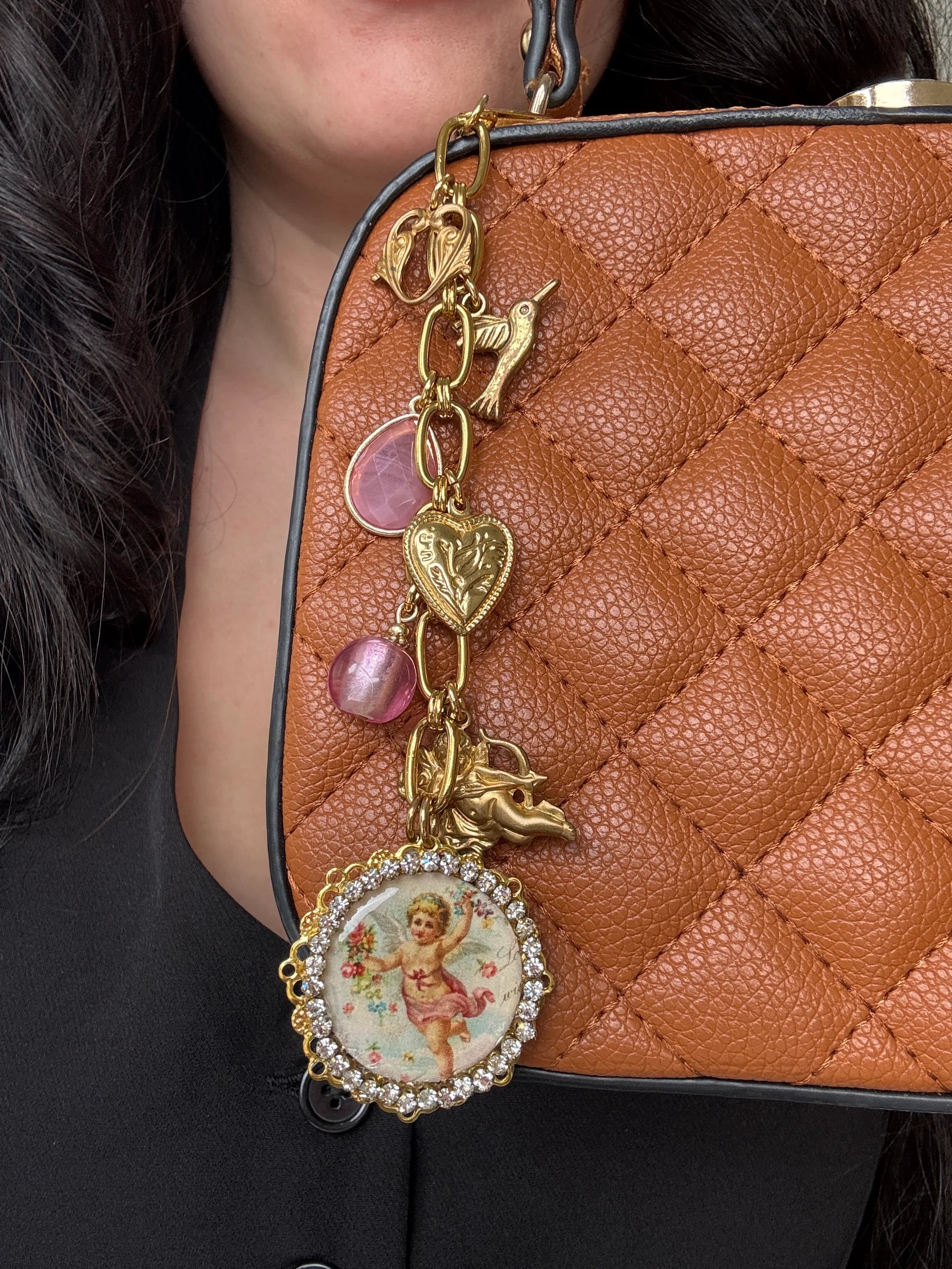 Gold plated charm keychain with vintage cherub, heart, and bird charms on a brown quilted purse, by Enleira