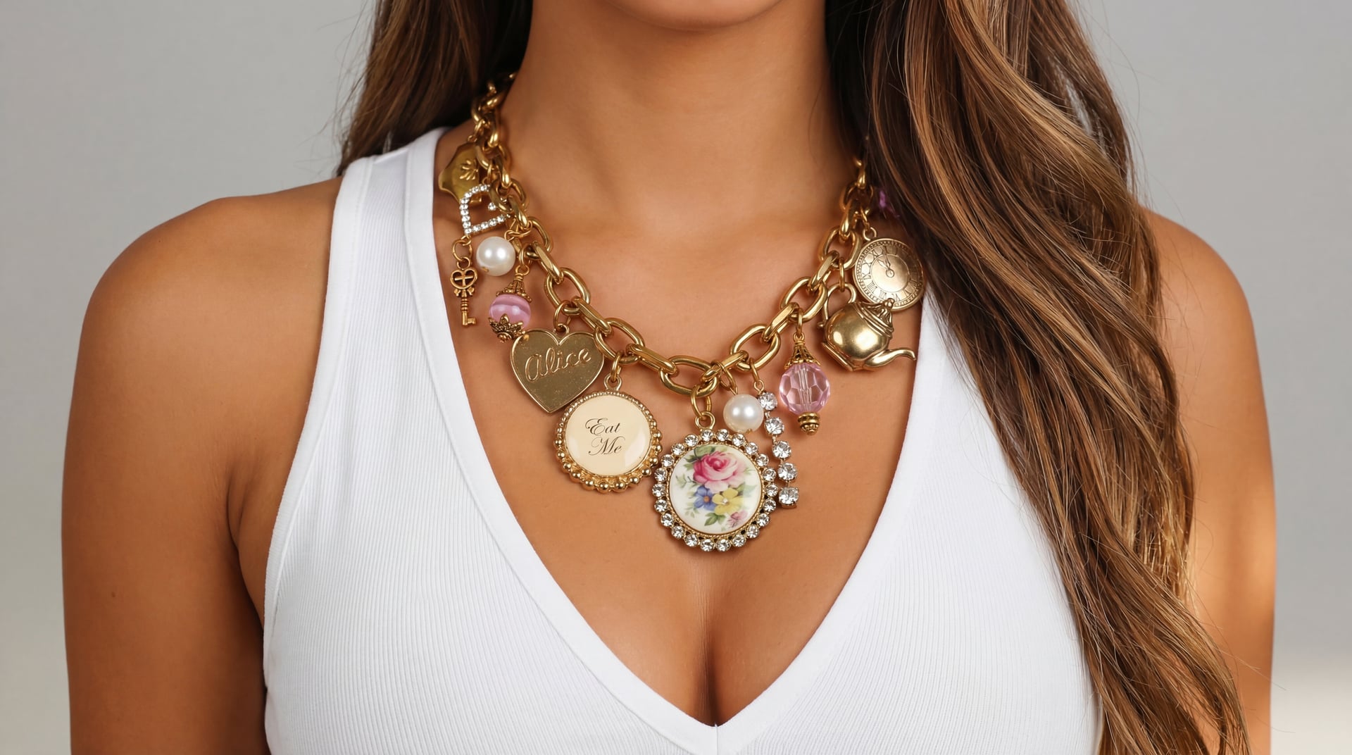 Handcrafted gold charm necklace and bracelet with pearl and flower charms, displayed by Enleira
