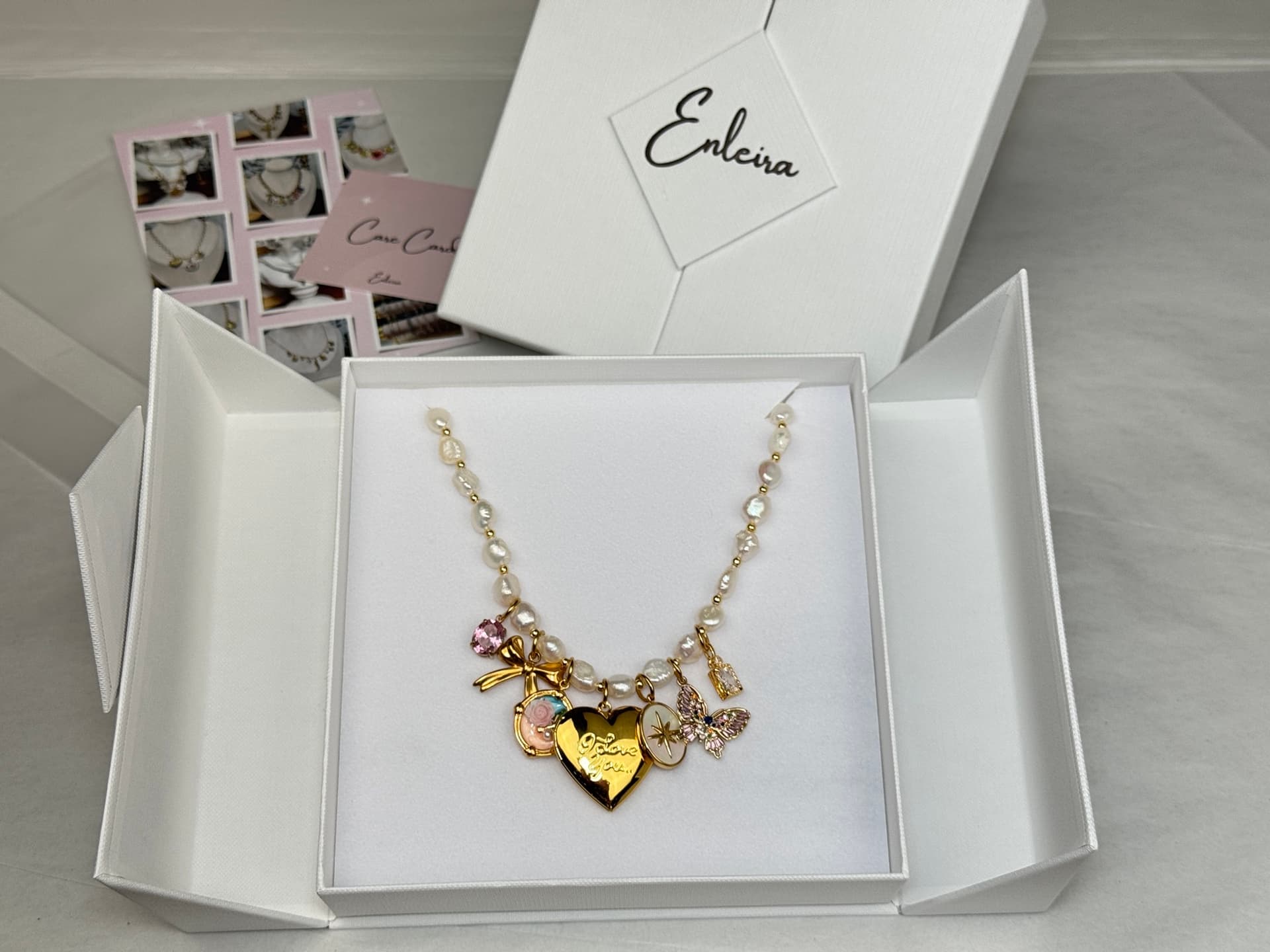 The Enleira jewelry box — white magnetic split-top with the Enleira wordmark