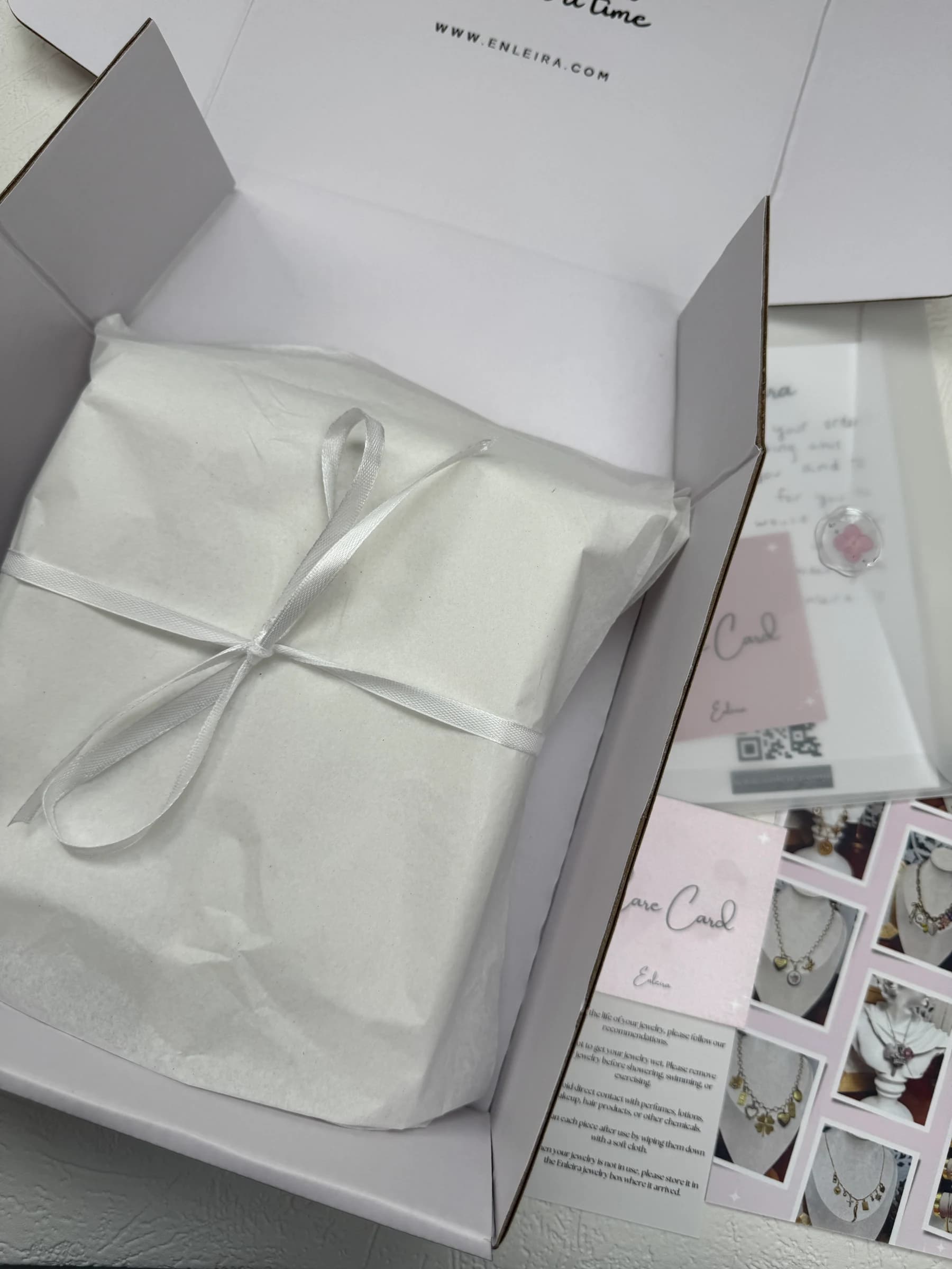 Elegant gift-wrapped jewelry in a white box with ribbon, by Enleira